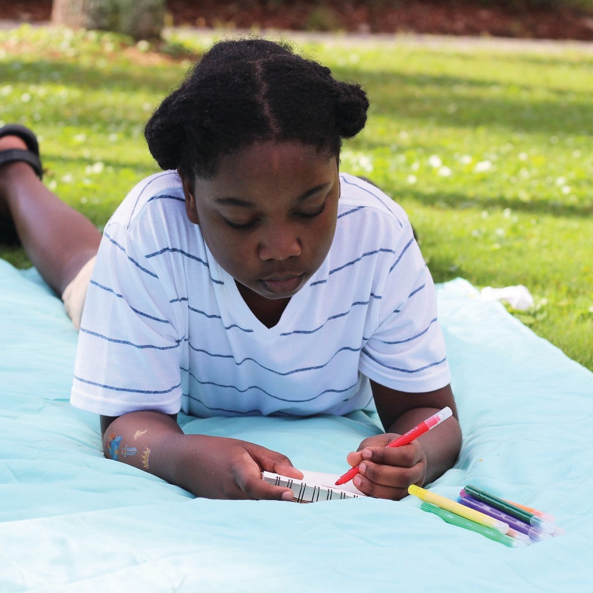 a child drawing outside in a notebook using Switcheroo color-changing markers with chiseled tips