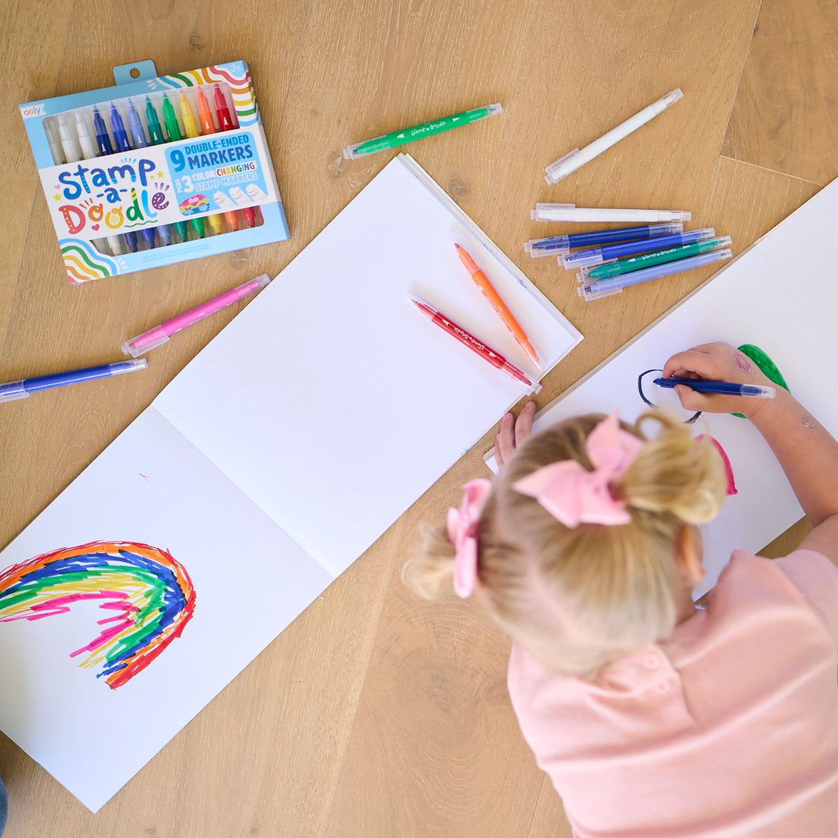 a girl drawing on the floor using the markers