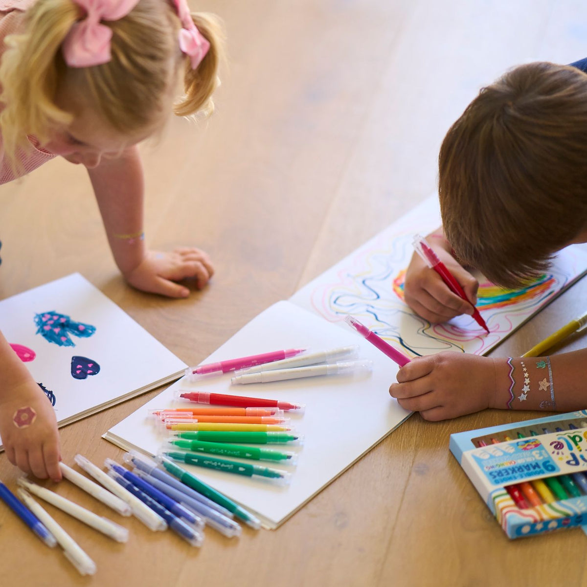 two kids on the floor drawing with markers