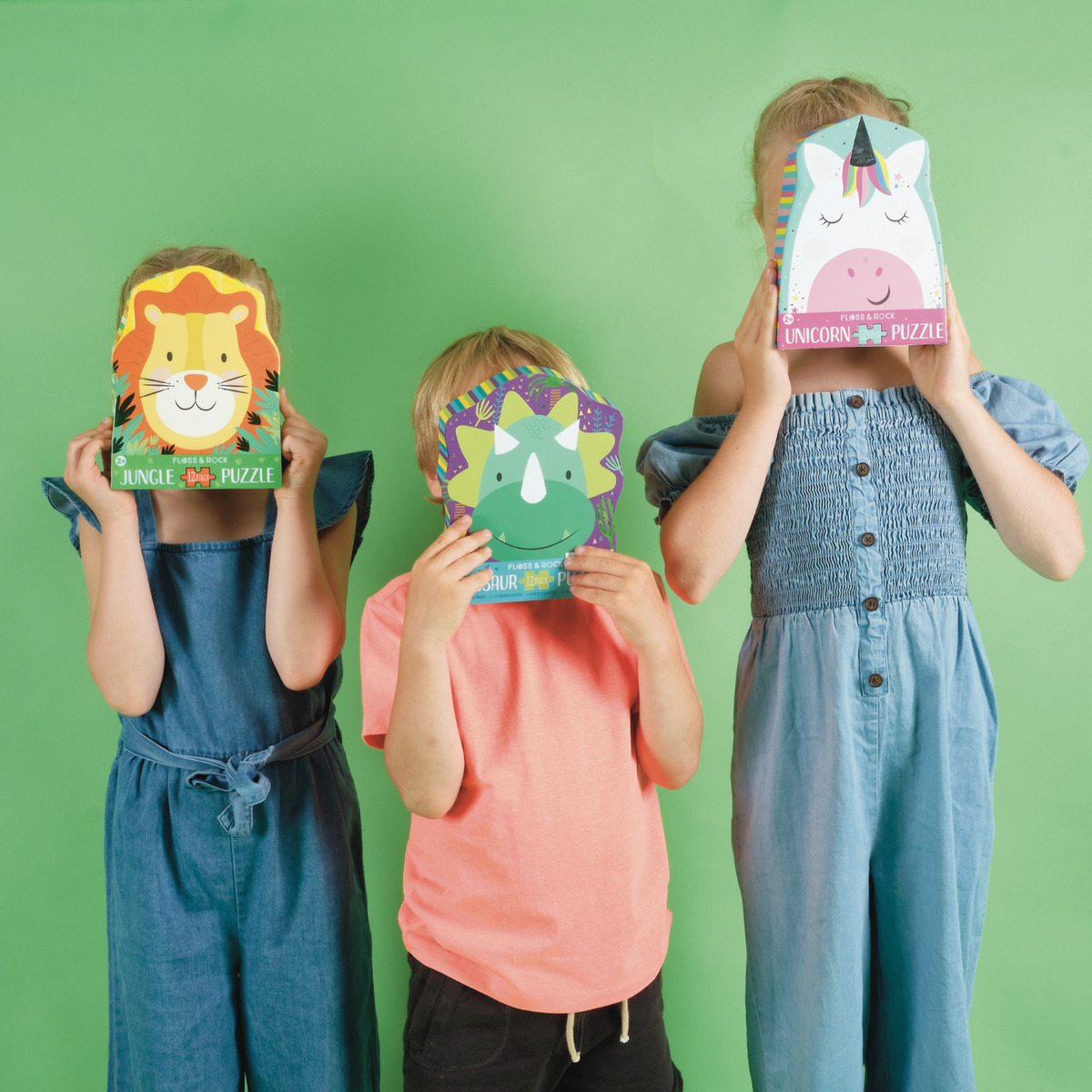 three kids holding 3 different puzzles on green background 