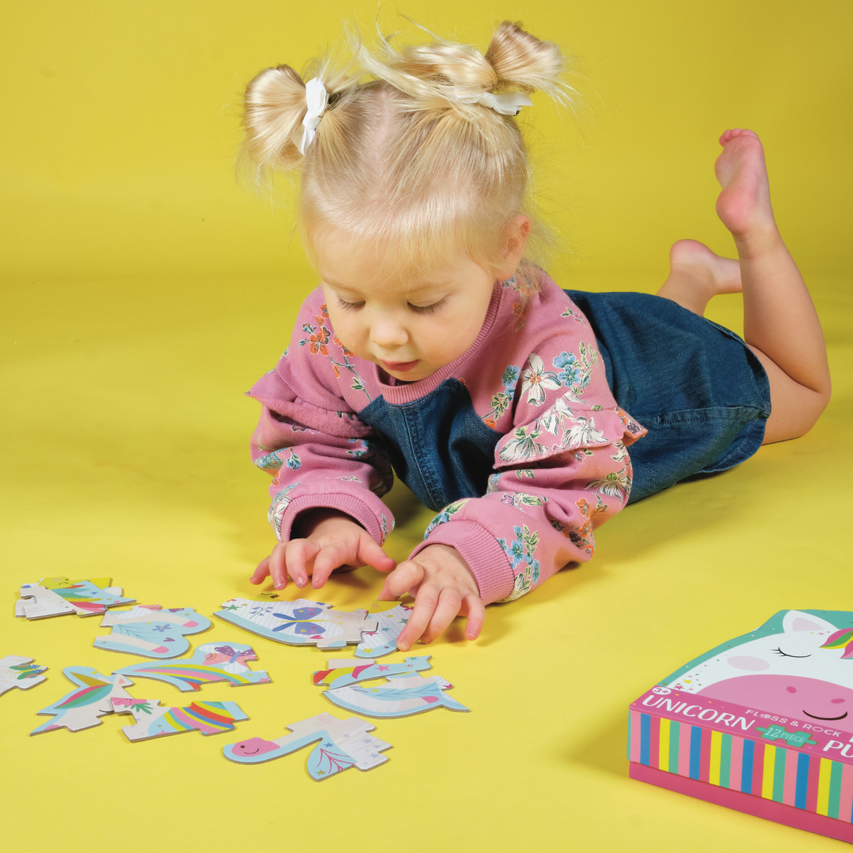 A little girl playing with A packaged 12 piece shaped puzzle depicting a colorful unicorn