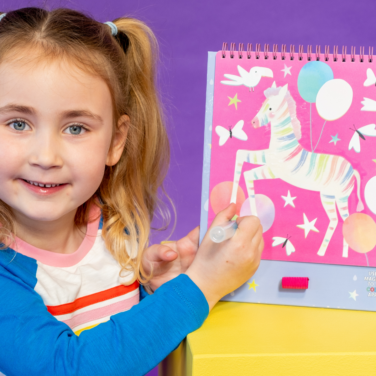 a girl colouring in A colorful Magic Water Easel Pad with a spiral binding and a pen, designed for color-changing activities.