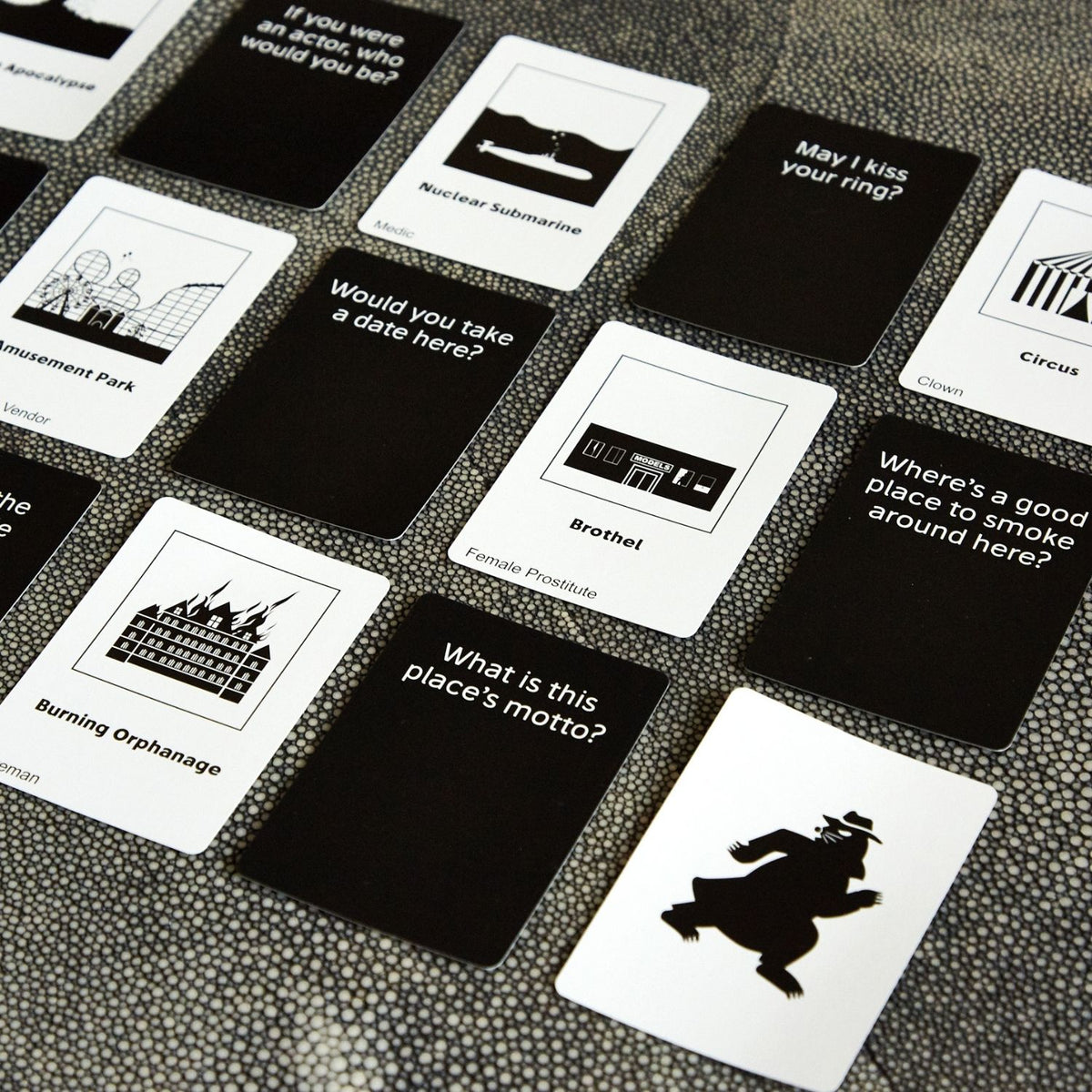 Collection of black and white cards with various questions and illustrations on a textured surface.