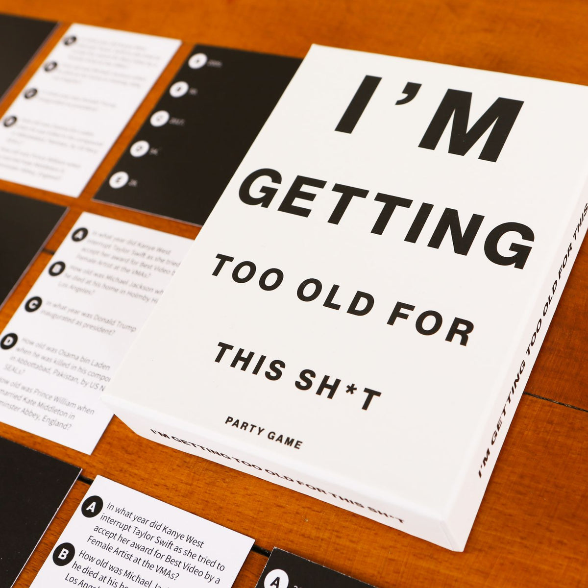 Game card with text 'I'm Getting Too Old For This Sh*t' on a wooden surface