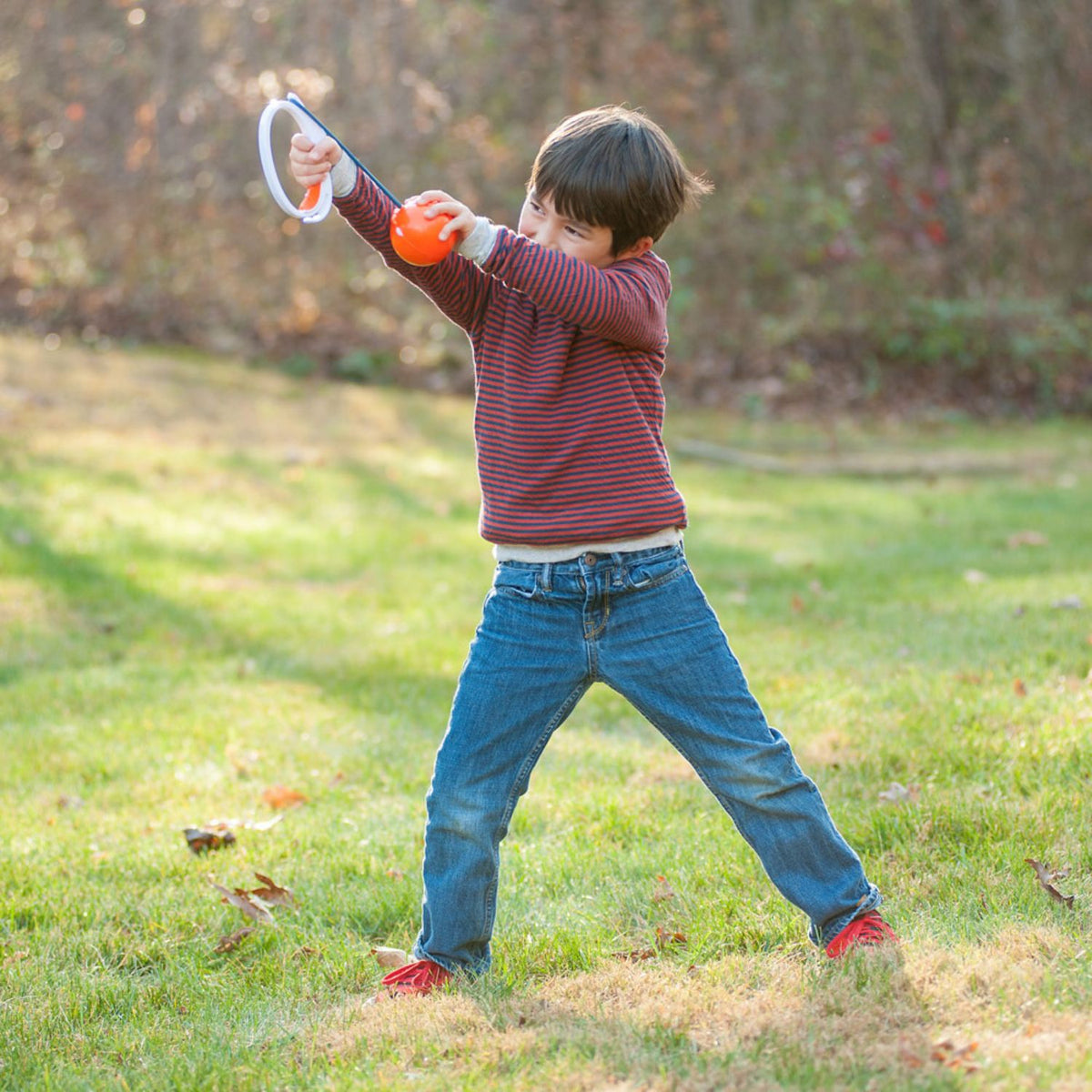 An action shot of a child pulling back the ParaShoot capsule against the launcher, demonstrating the vertical sling-shot mechanic.