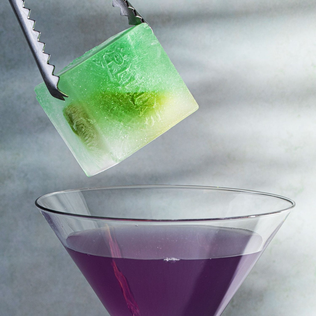 A single 47mm cube from a jumbo ice cube mould resting in a crystal glass, showcasing its slow-melting properties and bold aesthetic.