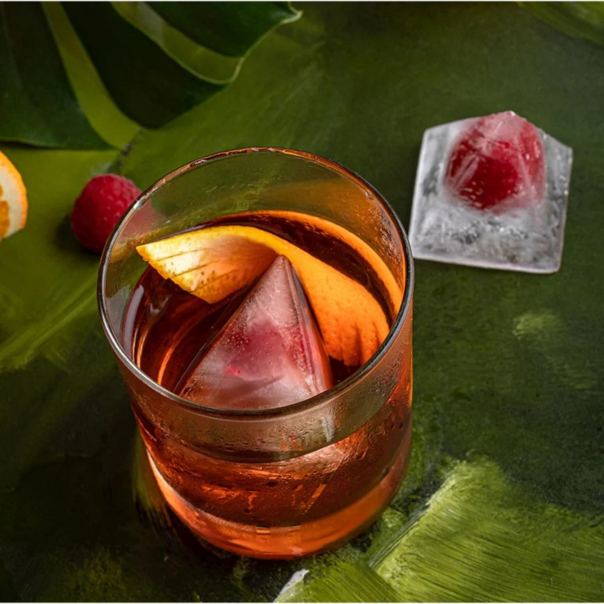 Cocktail with ice cubes and fruit.It has a "designer" feel. The sharp edges and flat faces catch the light differently than round ice, making the drink look like a piece of architectural art.