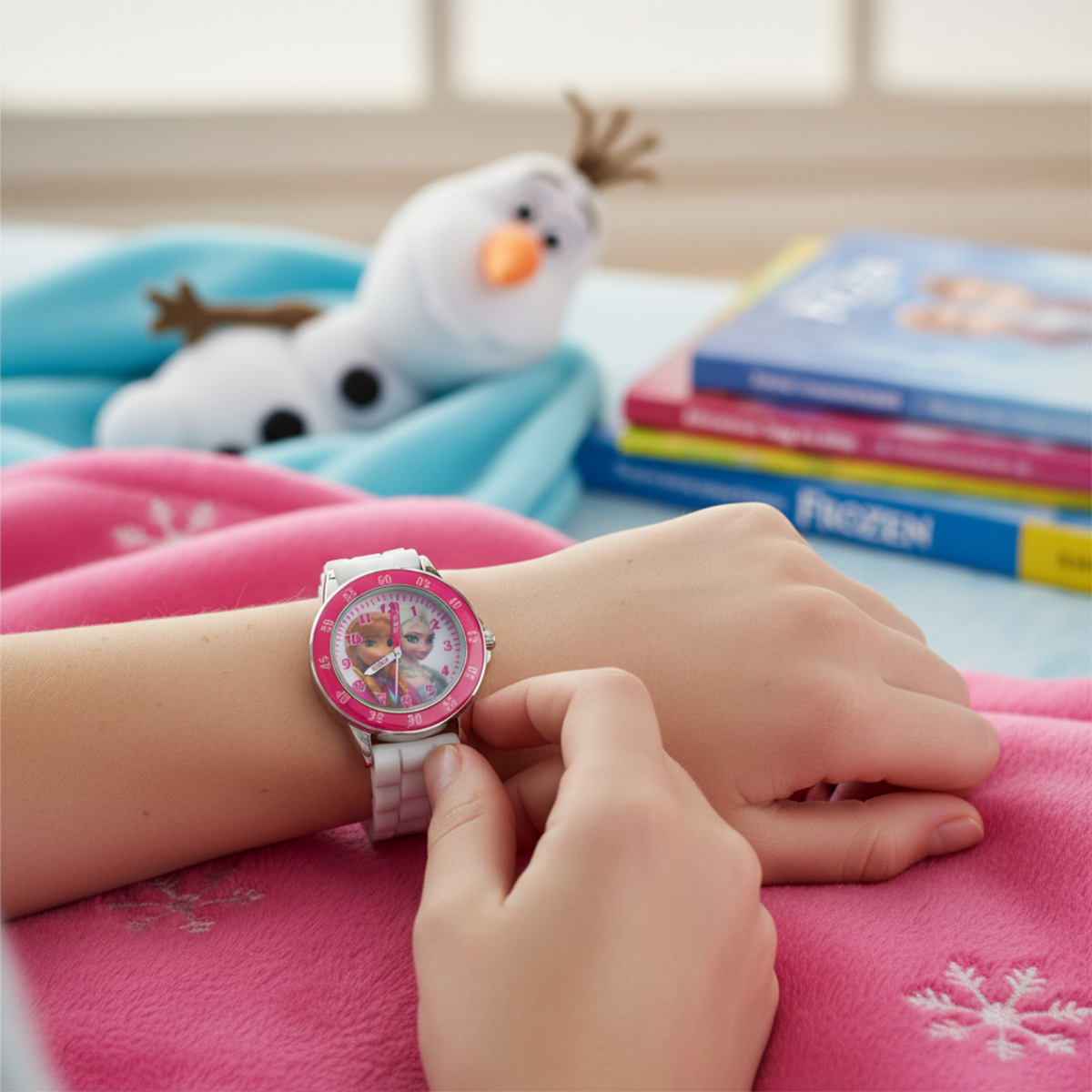 Child wearing a Frozen-themed watch with books and a plush toy in the background
