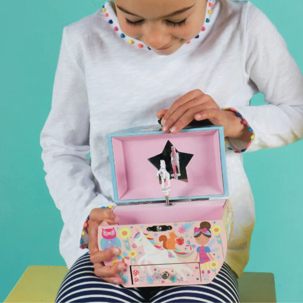 The open lid of the oval jewellery box showing a magical unicorn figurine twirling in front of a mirror to the tune of “You Are My Sunshine.”