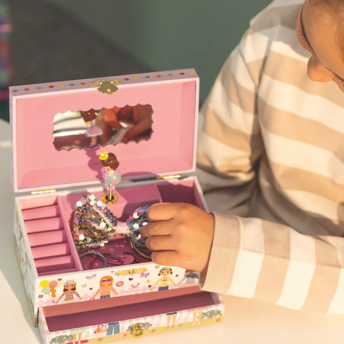 Child playing with a jewelry box filled with accessories