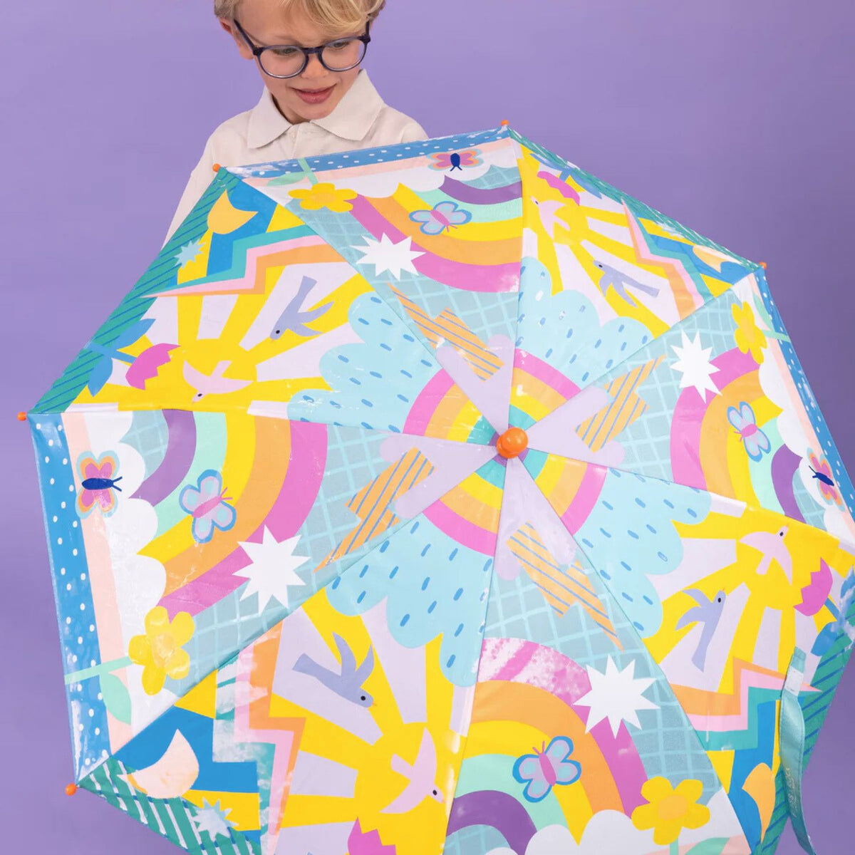 Child holding a colorful umbrella with rainbow patterns