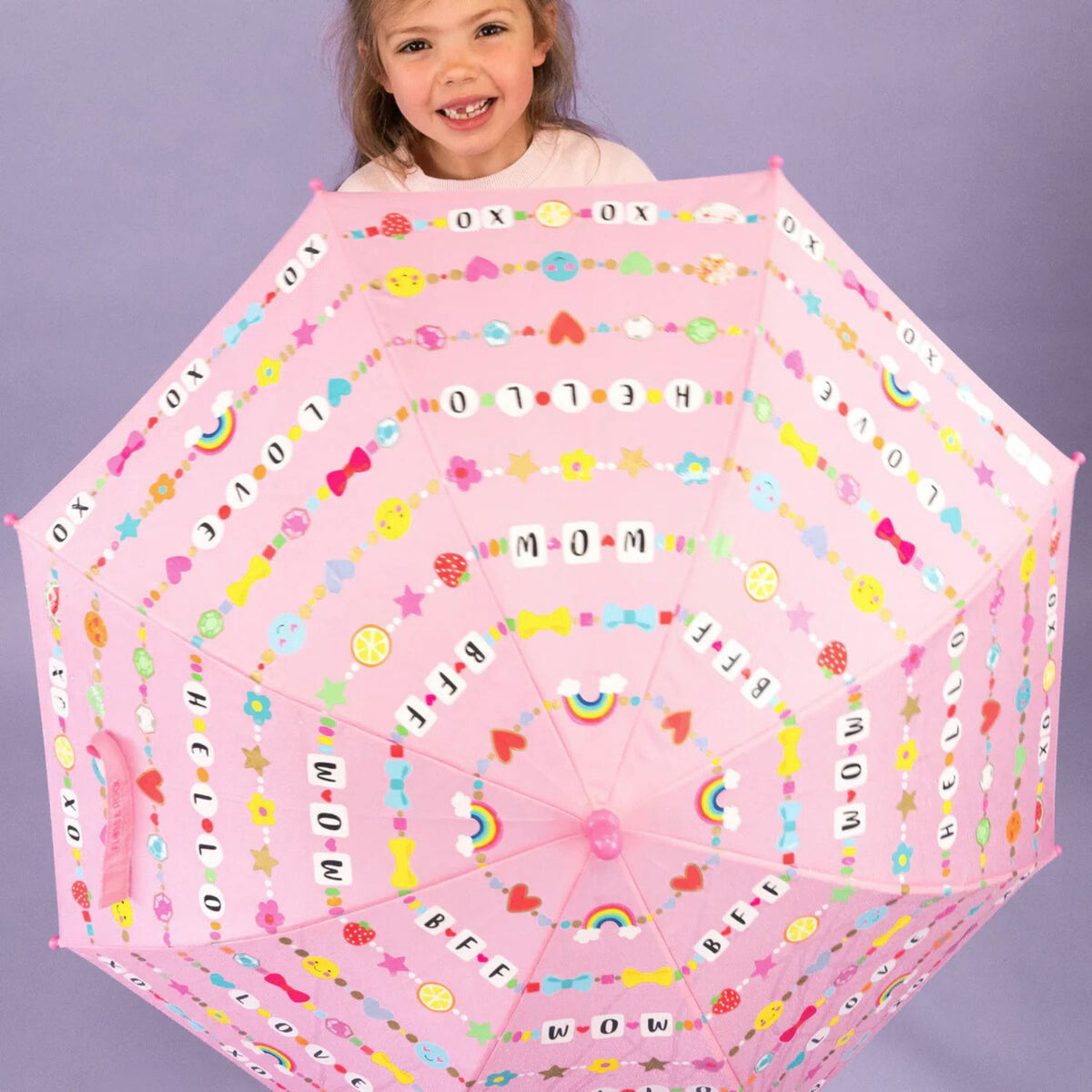 A child holding a pink colour changing umbrella that reveals hidden colours in the rain. Designed to make outdoor play more exciting for ages six and up.