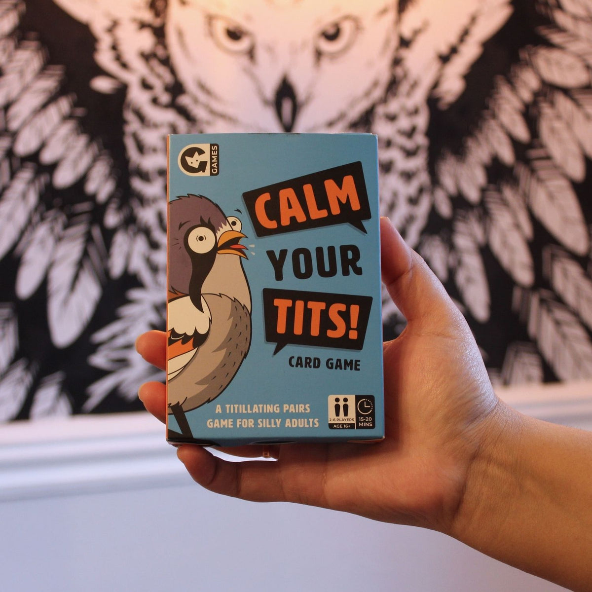 Hand holding a card game box titled 'Calm Your Tits!'
