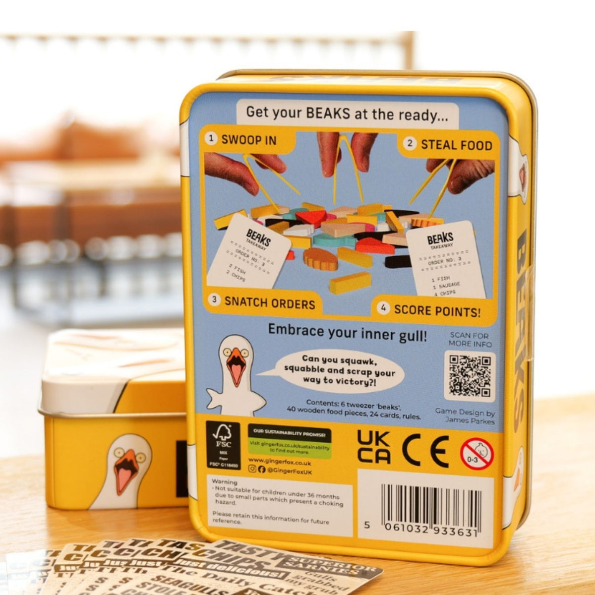 Game tin with toy beaks on a wooden surface