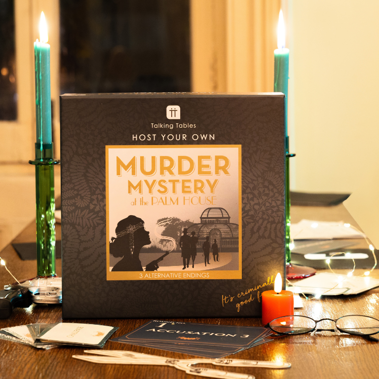 Murder mystery game box on a table with candles and cards