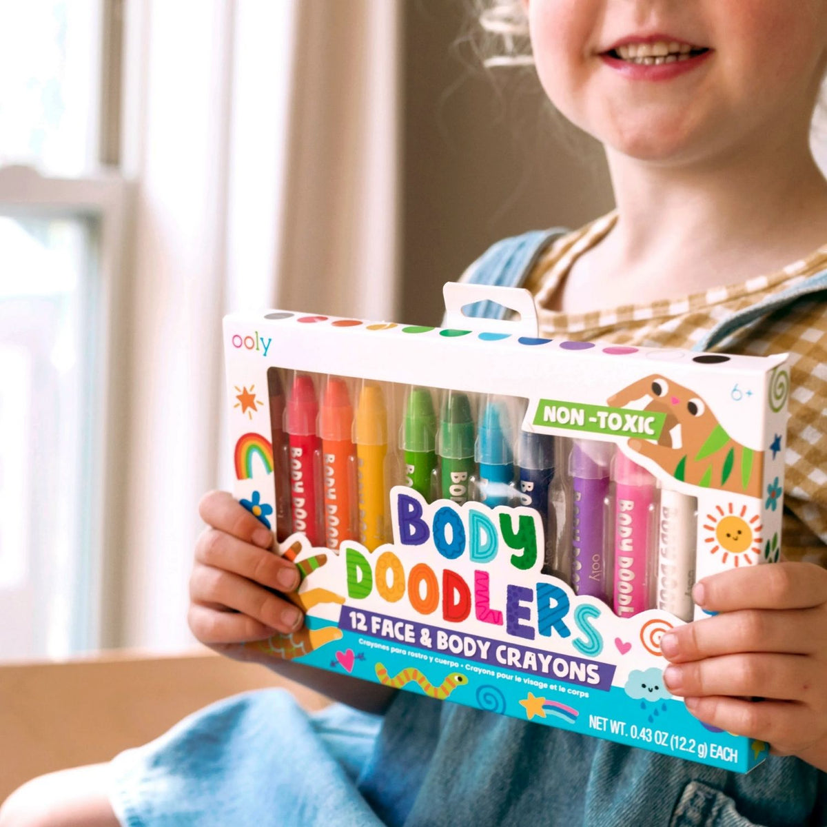 Child holding a package of Body Doodlers crayons with a neutral background