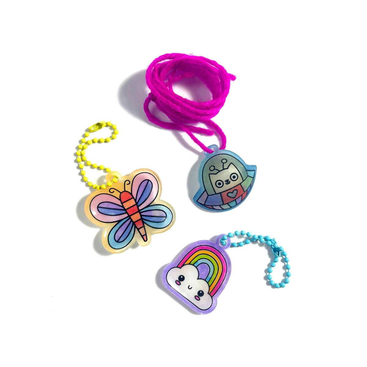 A collection of finished DIY charms, including a butterfly and a rainbow cloud, attached to colourful ball chains.