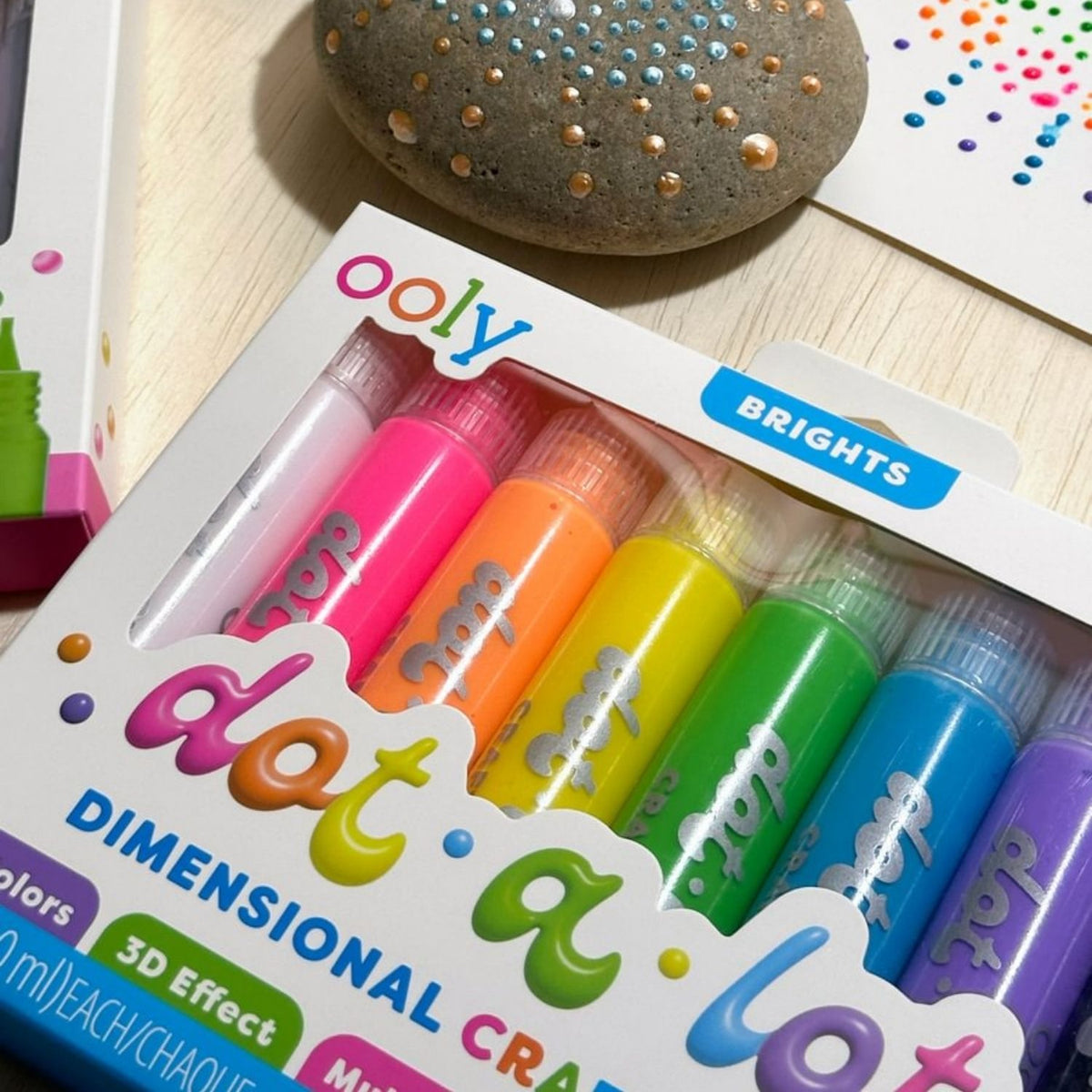 Set of colorful dimensional craft markers in packaging with 'ooly' branding showing how you can use them on rocks and paper