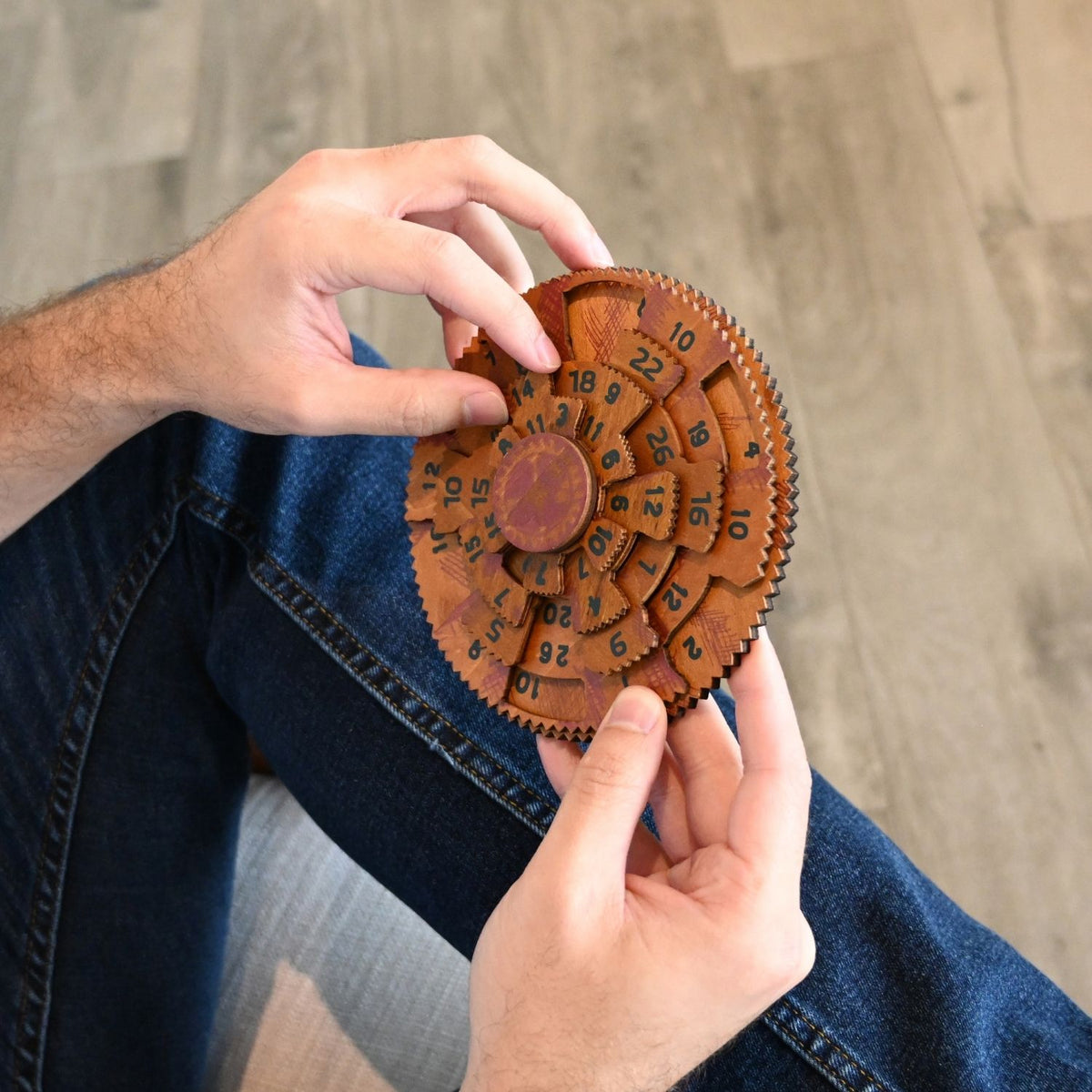 A person’s hands turning the wooden dials of the Grecian Computer, attempting to align the number columns to reach the sum of 42.