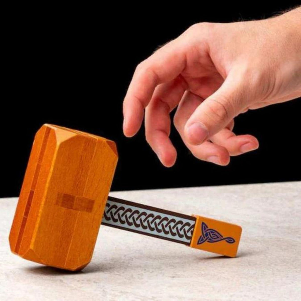 A person’s hands carefully sliding the wooden interlocking segments together to reconstruct the iconic Norse hammer.