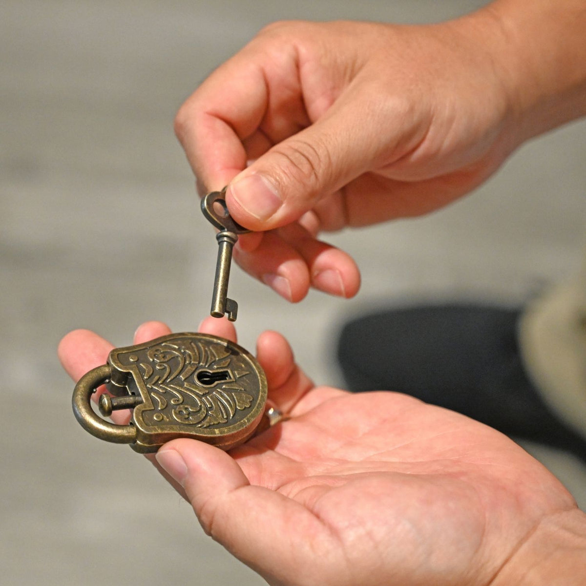 A person’s hands using a key to probe the internal mechanism of the level three difficulty Grecian trick lock to find the secret release.