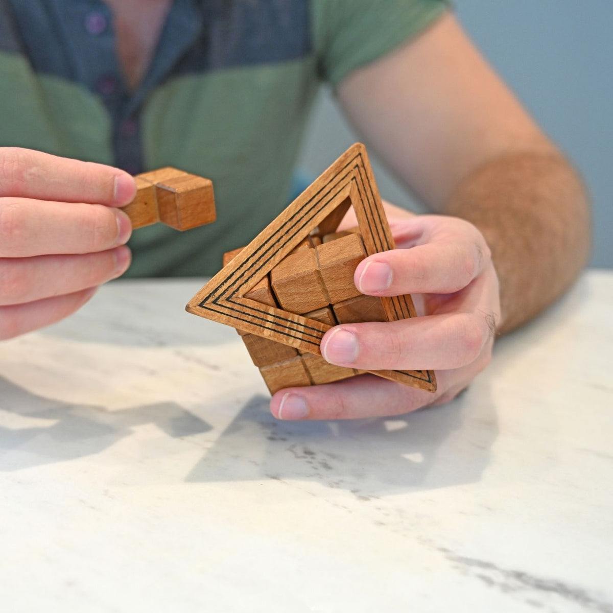Person assembling the wooden puzzle. Extract and reassemble the seven piece cube to test spatial reasoning. Level four difficulty