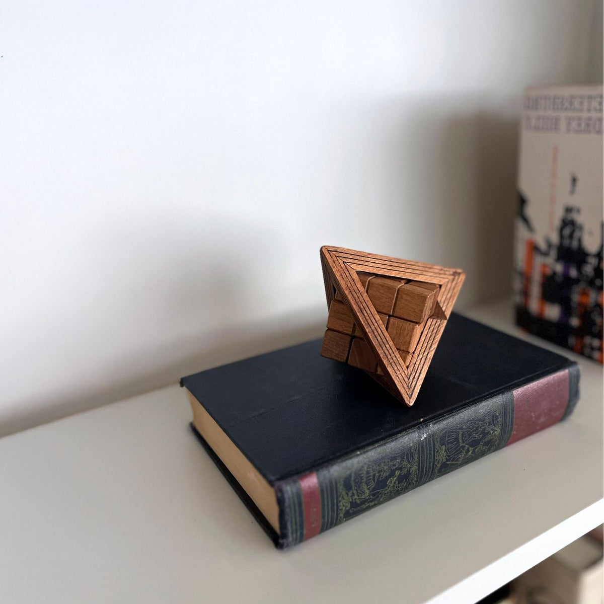 Wooden triangular puzzle on a book showing high quality and how to display