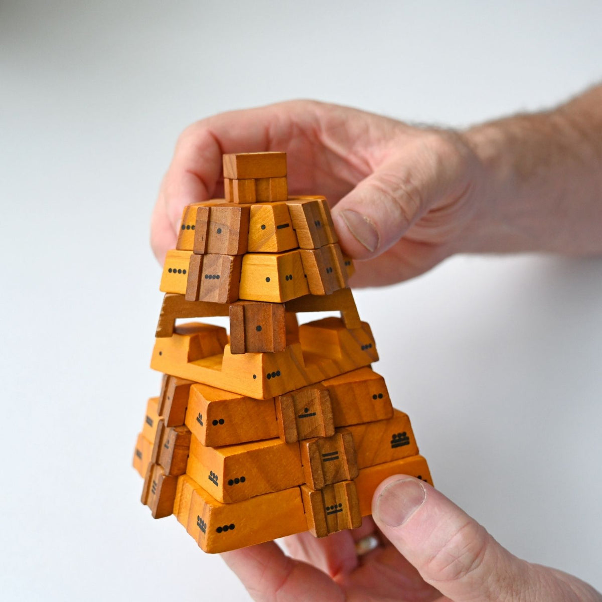 Hand holding a the wooden pyramid puzzle showing build quality and  educational maths puzzle