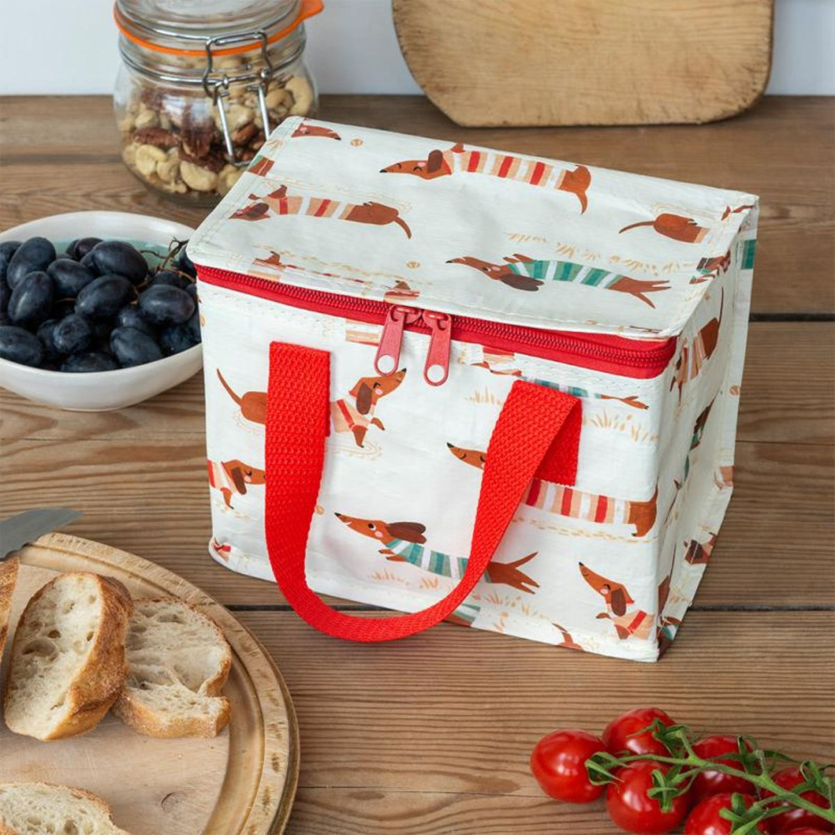 A lightweight insulated lunch bag with sausage dog print perfect for school or picnics. Features fun prints, a leak-resistant foil lining, and folds flat for easy storage.