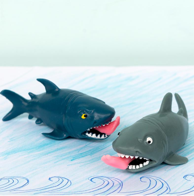 Two toy sharks with open mouths on a blue water-patterned surface